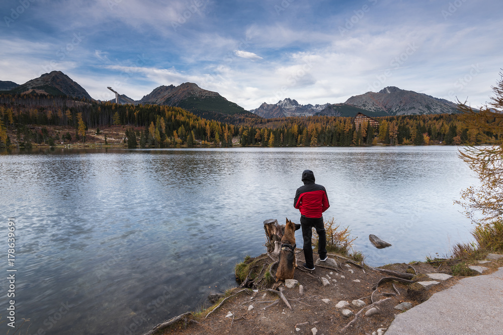 Wanderlust man and his dog looking over lake in high mountains Wanderlust man and his dog looking over lake in high mountains