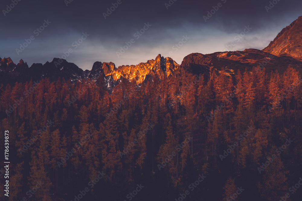 Last sun light hits high mountains peak at sunset
