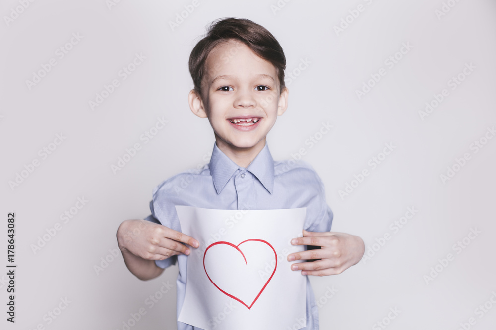 Portrait of young happy smiling brunette boy with picture of heart on the sheet of paper in hands looking at camera isolated. Portrait of young happy smiling brunette boy with picture of heart on the sheet of paper in hands looking at camera isolated.