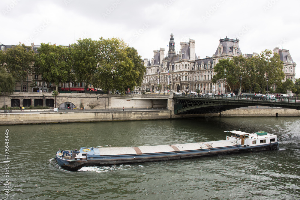 Barge and Tugboat cargo ship sailing in Seine river near old town Paris city and Hotel de Ville