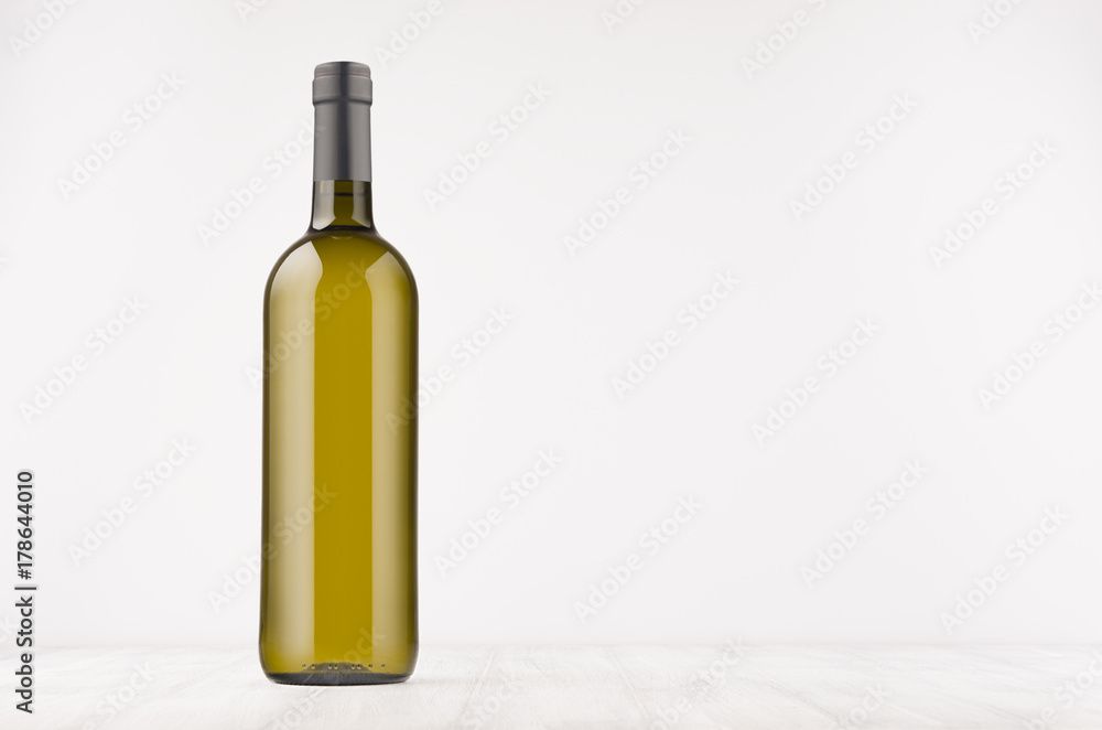 Green wine bottle with white wine on white wooden board, mock up. Template for advertising, design, branding identity. Green wine bottle with white wine on white wooden board, mock up. Template for advertising, design, branding identity.