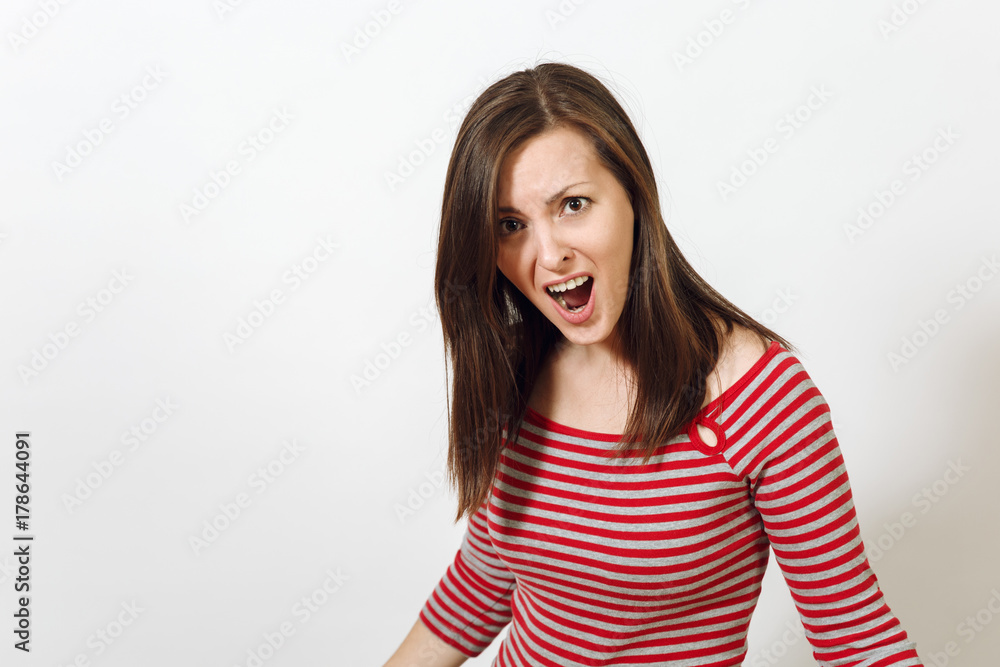 Pretty European young angry brown-haired woman with healthy clean skin, dressed in casual red and grey clothes, screaming, swearing and waving her arms, on a white background. Emotions concept. Pretty European young angry brown-haired woman with healthy clean skin, dressed in casual red and grey clothes, screaming, swearing and waving her arms, on a white background. Emotions concept.