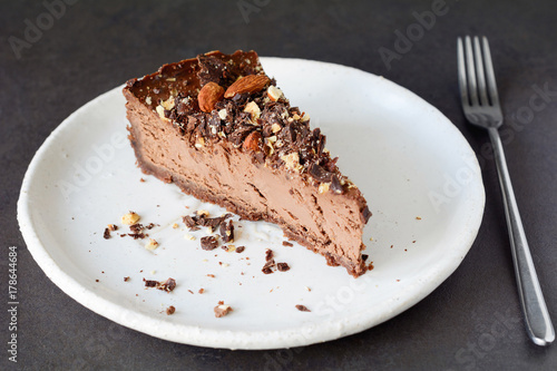Tableau sur toile Chocolate cheesecake slice with crushed nuts on white plate