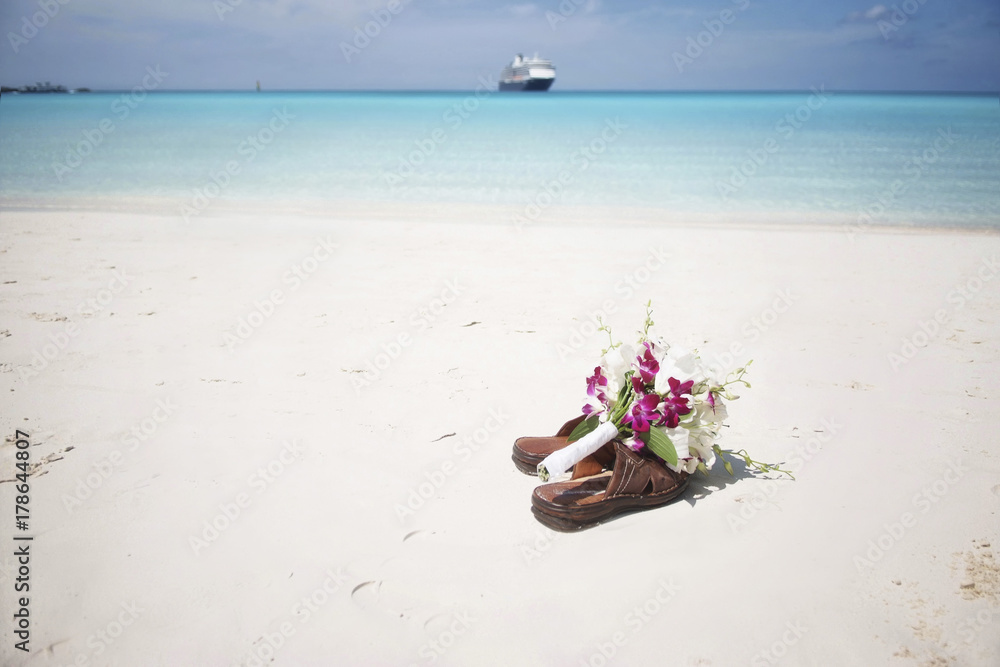 Bridal bouquet on flip flops at the beach and cruise ship at the far end. Bridal bouquet on flip flops at the beach and cruise ship at the far end.