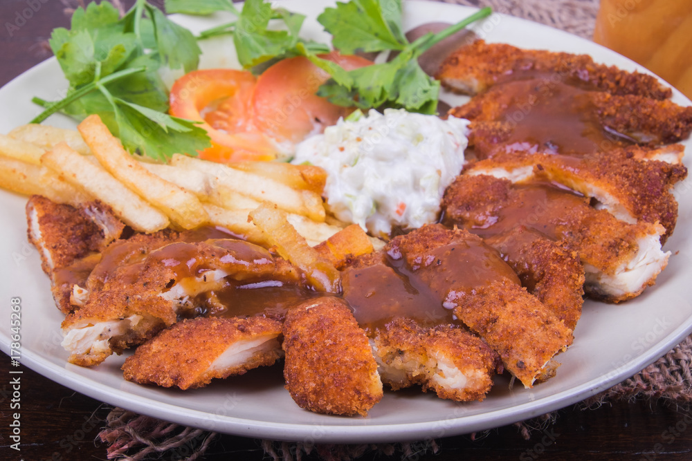 Chicken chop with vegetable and black pepper sauce in plate over wooden table