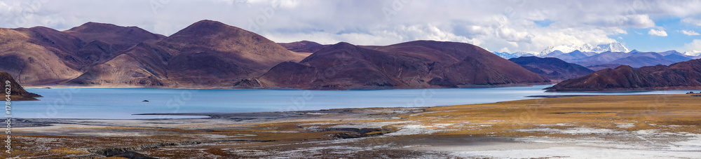 Panoramic view of holy lake Yamdrok with snowy mountains in the background- Tibet
