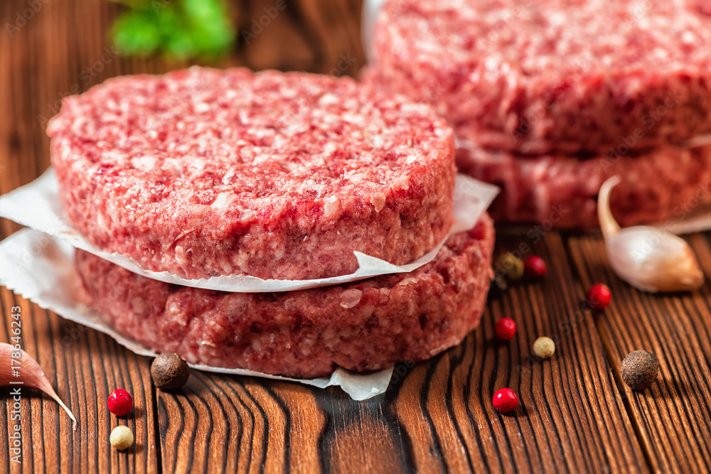 raw beef meat burger steak cutlets, dry pepper and garlic on rural wooden background raw beef meat burger steak cutlets, dry pepper and garlic on rural wooden background