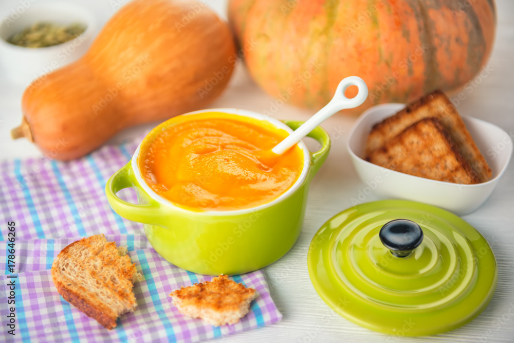 creamy pumpkin soup and bread in green bowl on napkin, concept of healthy eating creamy pumpkin soup and bread in green bowl on napkin, concept of healthy eating