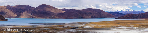 Panoramic view of holy lake Yamdrok with snowy mountains in the background- Tibet