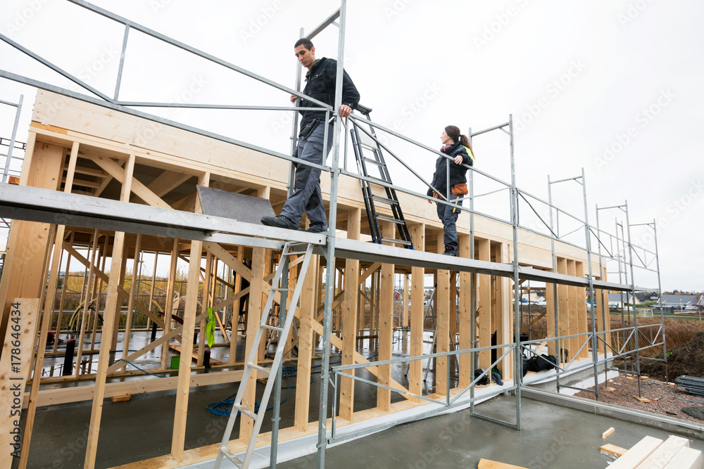 Colleagues Walking On Scaffolding At Construction Site