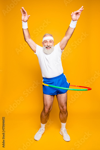 Emotional cool cheerful excited crazy funny fooling playful gymnast grandpa with comic grimace, exercises for fit figure. Body care, hobby, weight loss, game process photo