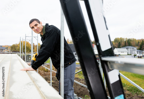 Confident Carpenter Drilling Wooden Roof At Construction Site