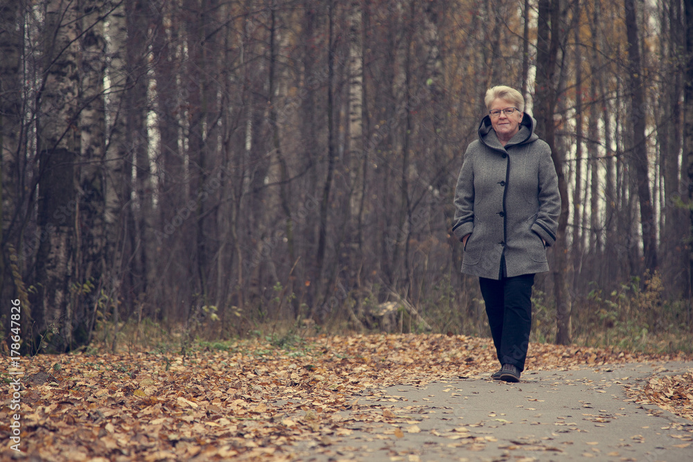 elderly woman in coat walking in the Park elderly woman in coat walking in the Park