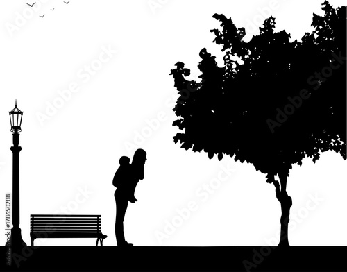 Mother carrying a child piggyback in park, one in the series of similar images silhouette