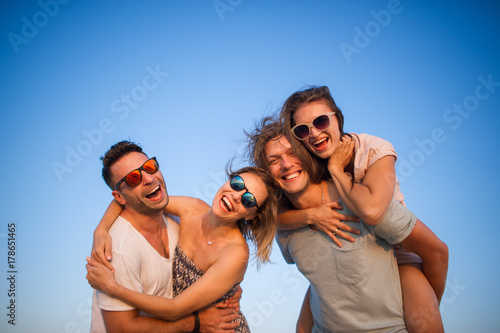 Four cheerful young people against the background of the blue sky.