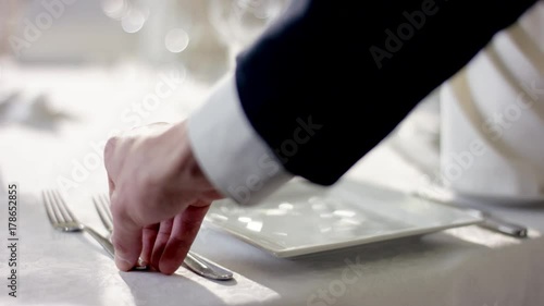 Shot of waiter hand preparing the dinner table before celebration at restaurant photo