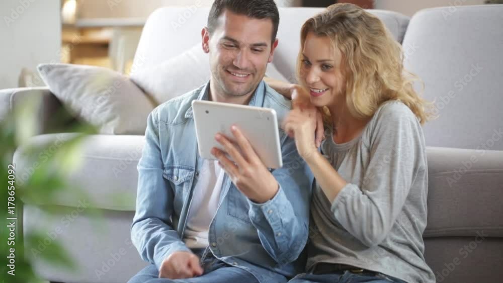 Relaxed young couple using a tablet in their living room Relaxed young couple using a tablet in their living room