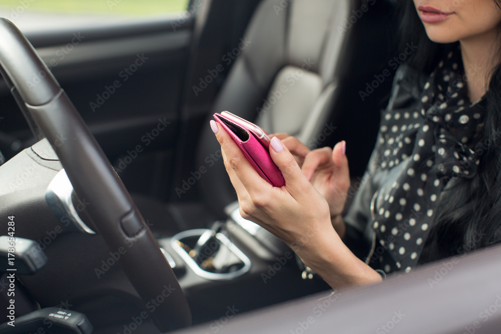 Close up hand woman using mobile smartphone. Blurred car interior background.