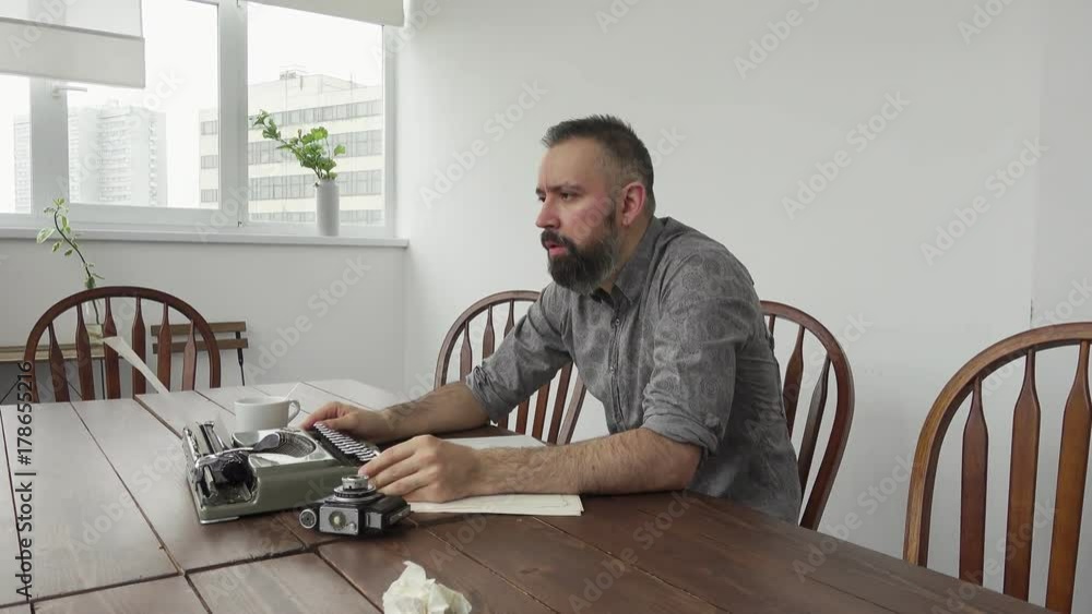 Male writer looking for inspiration and typiing on the typewriter Male writer looking for inspiration and typiing on the typewriter