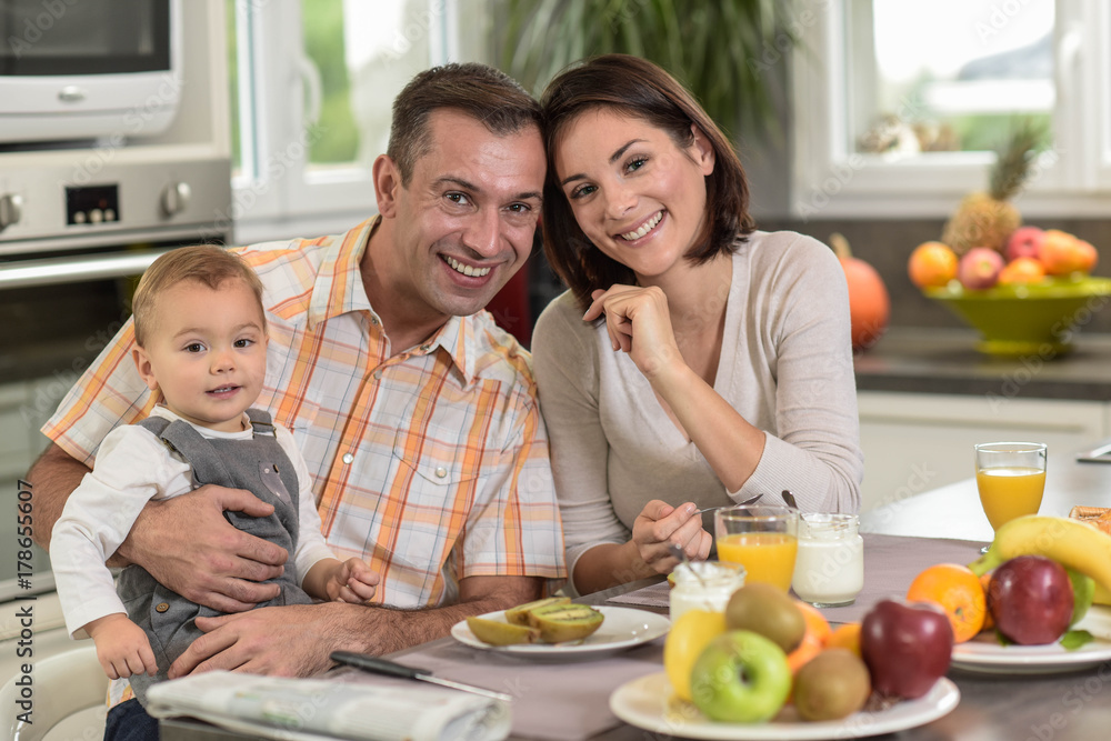 Young family  having breakfast in the kitchen with a baby