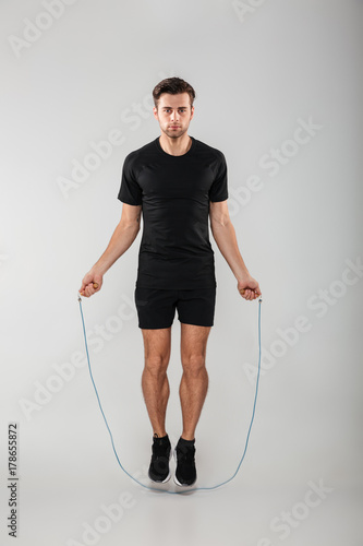 Obraz na plátně Strong young sports man jumping with skipping rope