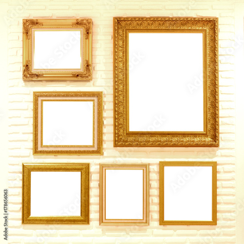 empty golden picture frames on brick wall
