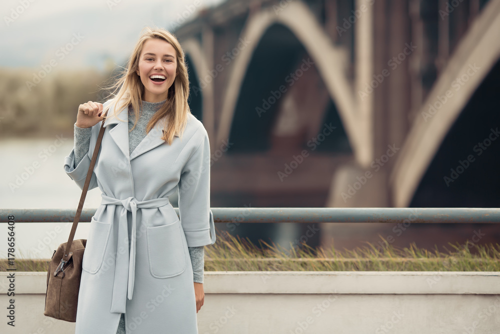 Young woman in blue coat. Autumn city background. - obrazy, fototapety, plakaty 