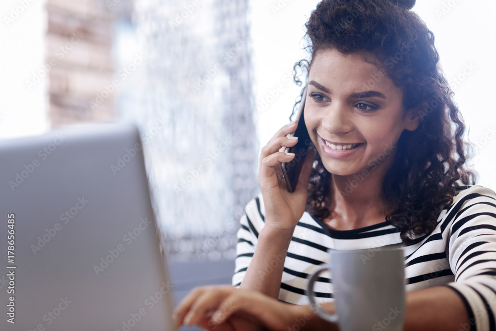Fototapeta premium Happy curly-haired girl talking on the phone