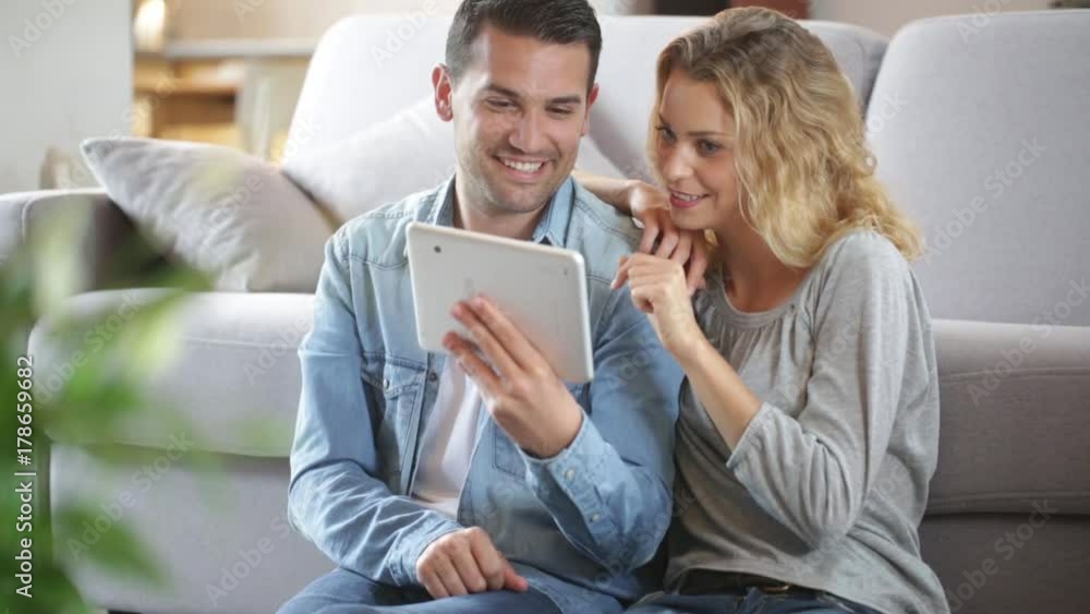 Relaxed young couple using a tablet in their living room Relaxed young couple using a tablet in their living room