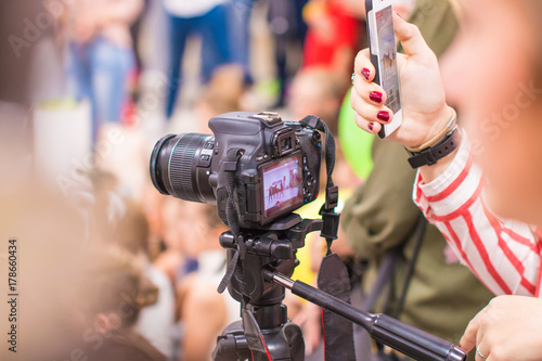 The girl shoots on the camera and takes pictures on the phone