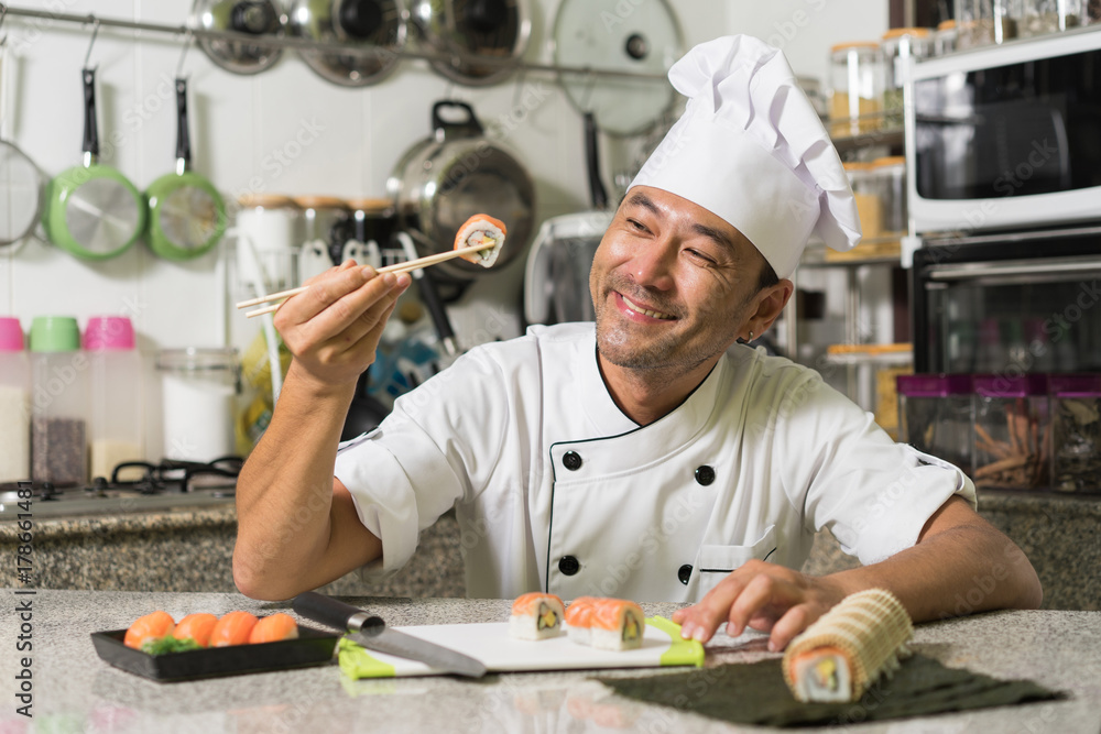Smiling asian chef with sushi and rolls on kitchen. Focus on the face. Smiling asian chef with sushi and rolls on kitchen. Focus on the face.