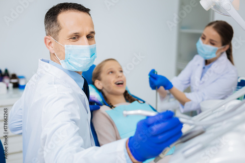 Positive skillful dentist working with his colleague