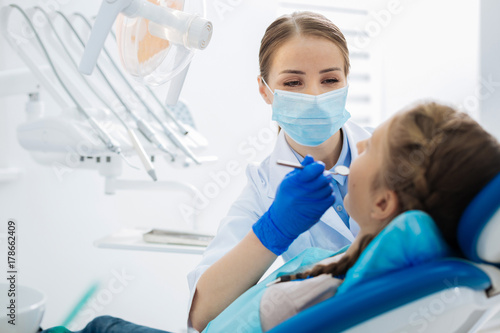 Photos Positive female dentist being at work
