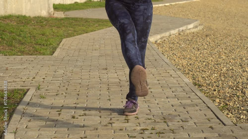 Female legs in dark blue leggings jump over the rope for the path next to the stony beach. Workout, outdoor activities in open air, slow motion. Female legs in dark blue leggings jump over the rope for the path next to the stony beach. Workout, outdoor activities in open air, slow motion.