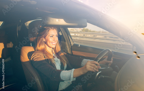 Beautiful businesswoman driving car at sunset