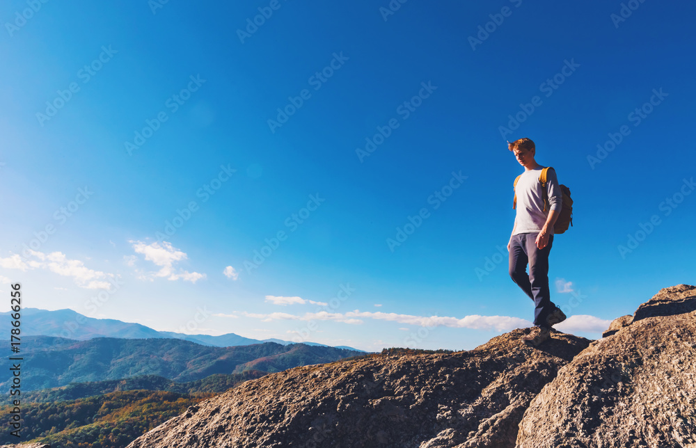 Man walking on the edge of a cliff high above the mountains
