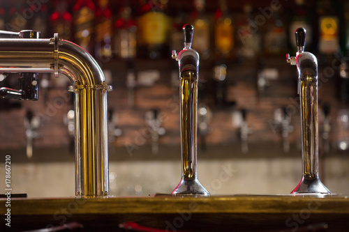 bar counter with beer taps on wall background with bottles