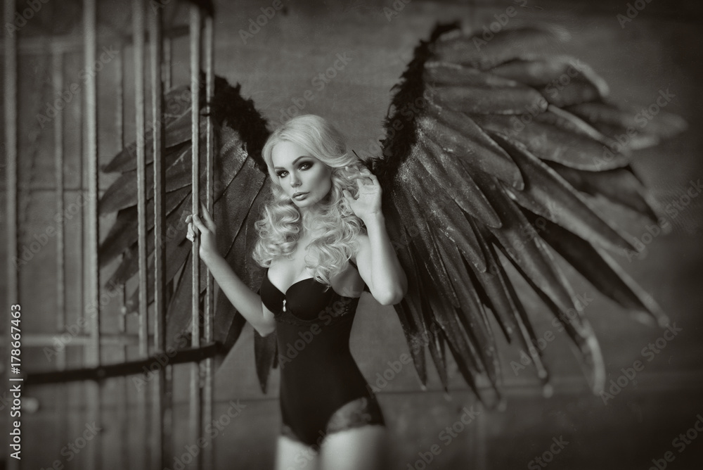 Obraz premium blond woman with black wings in a cage. Angel, mysticism