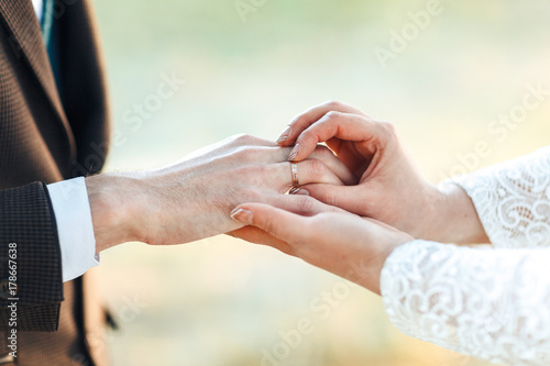 The hands of the newlyweds. A womens's hand puts on a ring. wedding ceremony. Bride hands close-up. © lena_itzy