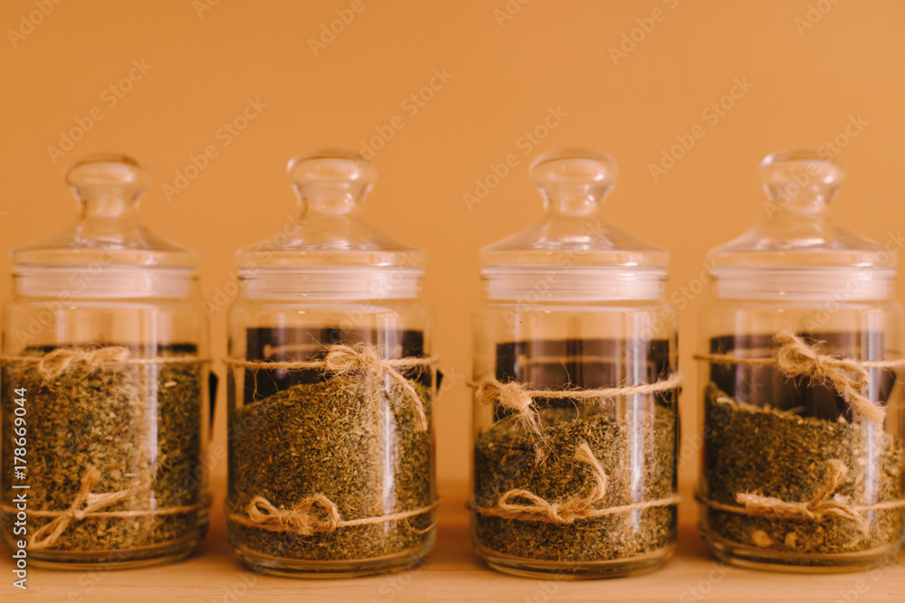 Set of different spices and herbs in glass jars on wooden wooden shelf. Curry, saffron, turmeric, pepper, salt and rosemary. Set of different spices and herbs in glass jars on wooden wooden shelf. Curry, saffron, turmeric, pepper, salt and rosemary.