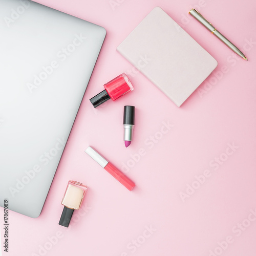 Home feminine desk with laptop, notebook and cosmetics on pink background. Top view. Flat lay lifestyle concept.