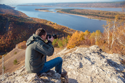 a man stands on top of a mountain and takes a picture of the landscape