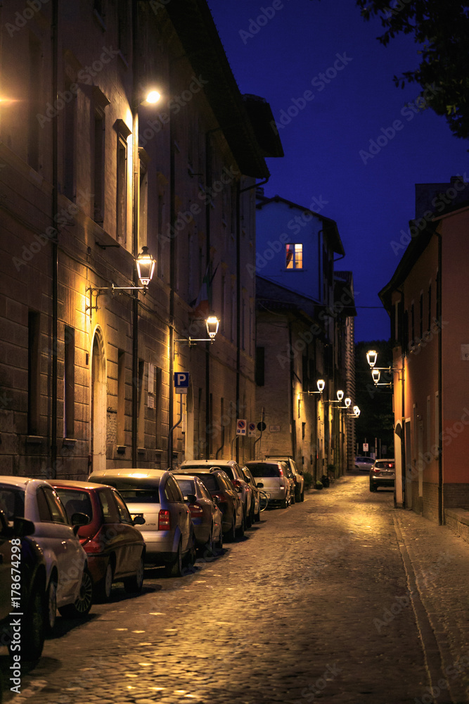 Fano, Italy - August 8, 2017: narrow street lit by street lamps at night in the old town.