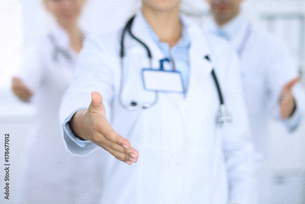 Group of doctors offering helping hand. Female physician at the front fokus. Partnership and trust concept in medicine and health care Group of doctors offering helping hand. Female physician at the front fokus. Partnership and trust concept in medicine and health care