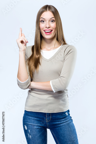 Beautiful young woman pointing up over white background.