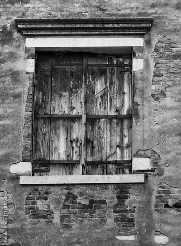 old black shuttered window set in a cracked wall