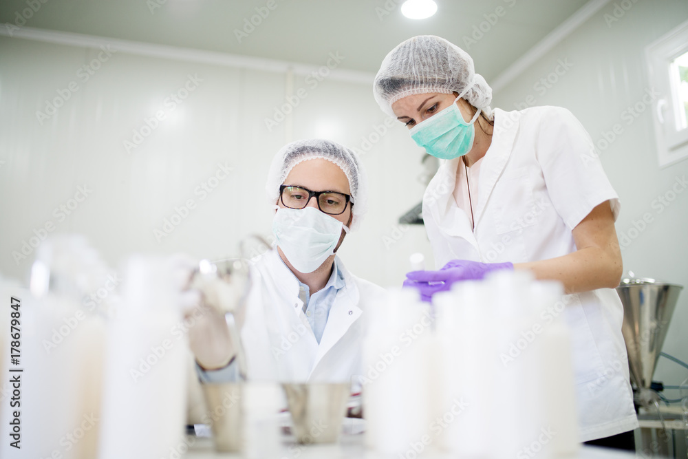 Two protected scientists checking new product with a funnel in the laboratory. Two protected scientists checking new product with a funnel in the laboratory.