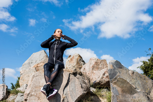 woman sitting on rocks and listening music