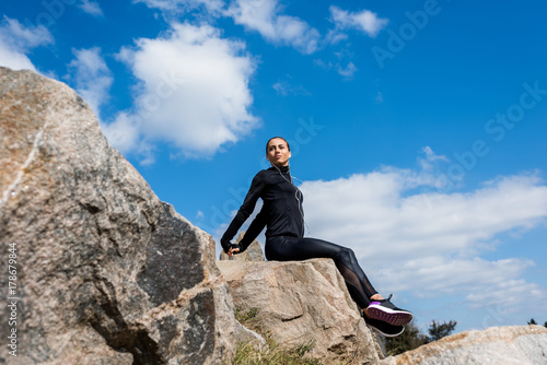 sportive woman sitting on rocks
