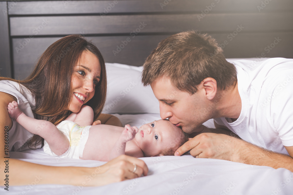 Mother father and baby child on a white bed. Mother father and baby child on a white bed.